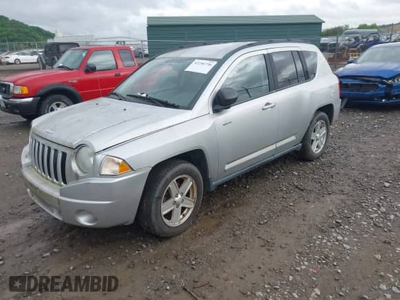 2010 Jeep Compass Sport z VIN 1J4NT1FBXAD621049, wystawiony jako IAAI lot #42256736 z przebiegiem 99 000 mil mil oraz . Historia ofert i sprzedaży dostępna na DreamBid. Obrazek 2.