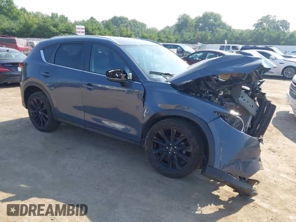 2022 Mazda CX-5 S Carbon Edition z VIN JM3KFBCM8N1565249, wystawiony jako IAAI lot #42739878 z przebiegiem 27 500 mil mil oraz . Historia ofert i sprzedaży dostępna na DreamBid. Obrazek 1.