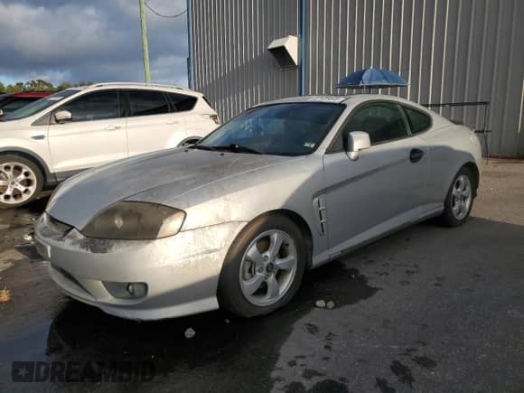 2006 Hyundai Tiburon GS z VIN KMHHM65D06U205823, wystawiony jako Copart lot #87125445 z przebiegiem 158 410 mil mil oraz Czysty tytuł • Clean title. Historia ofert i sprzedaży dostępna na DreamBid. Obrazek 1.